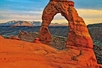 An impressive arch formation in the rock with the sunset and mountains in the background on the Arches National Park Sunset Discovery Tour Moab Utah.