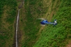 A helicopter flying by a cliffside with a small waterfall flowing over the edge on Big Island's Kohala Coast Adventure Helicopter Tour in Hawaii USA.