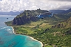 A helicopter flying along the coastline of Oahu with views of the mountains in the background on the Blue Skies of Oahu Helicopter Tour in Hawaii USA.