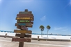 Wooden sign at the beach pointing out different sites
