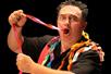 Man with his mouth open pulling multicolored ribbon out of it at Magic Show Starring Michael Bairefoot in Myrtle Beach, South Carolina, USA.