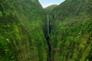 A waterfall flowing between two mountains into a crevice on the Maui Spectacular Helicopter Tour in Hawaii USA.