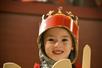 A child is dressed up as a knight with a crown, sword, and shield
