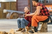 A child sits with a lumberjack on a stump