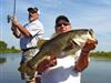 Two men on the Trophy Bass fishing trip, holding a pole and their catch