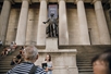 The tour group looking at the statues outside of Federal Hall on the Wall Street Through Time Walking Tour: From Alexander Hamilton to the Fearless Girl in New York City, New York, USA.