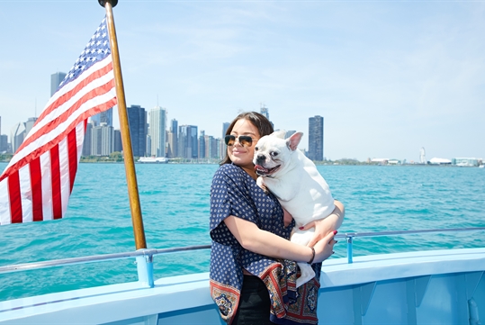 A woman holding her dog on the cruise with Chicago in the background on the Canine Cruise in Chicago Illinois.