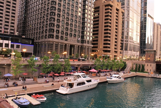 The Riverwalk Wine Garden and surrounding buildings with boats parked in the water out front as seen on the Chicago Riverwalk: Birthplace of Chicago walking tour in Chicago Illinois, USA.