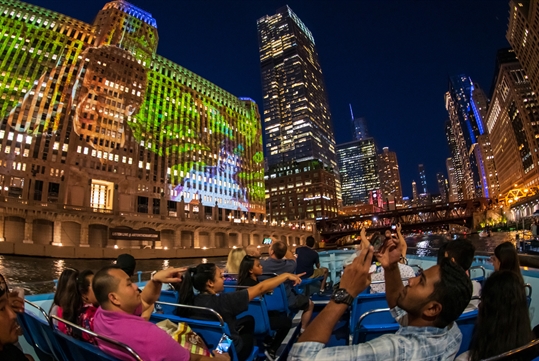 Guests looking at the night lights of Chicago on the Chicago by Night Cruise in Chicago Illinois.