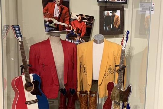 Buck Owens guitars and costumes in a display case at the Country Music Rediscovered Museum.