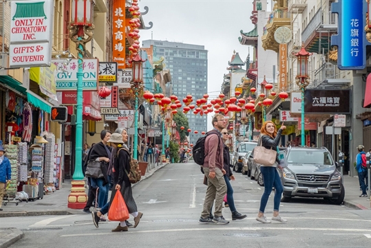 People exploring Chinatown with the buildings and lanterns in the background on the San Francisco Chinatown Tour: Through the Dragon's Gate, San Francisco California, USA.